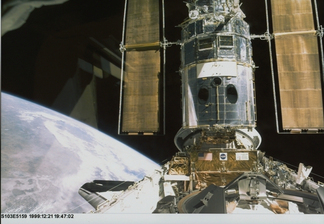 Hubble amarré à la navette américaine lors de la mission STS-103 en 1999. Crédits : NASA.